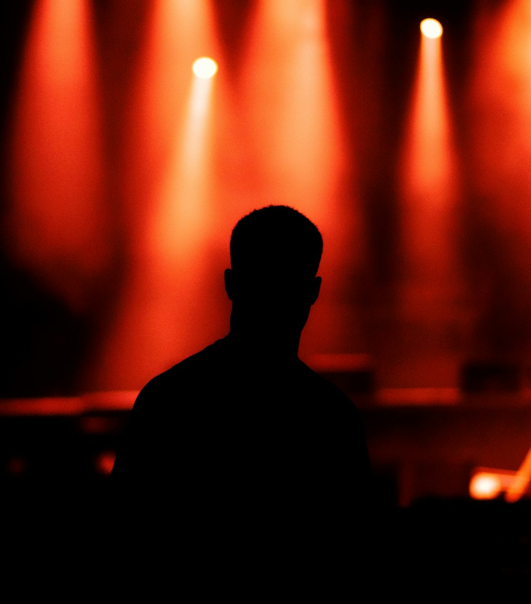 silhouette of man standing in front of stage lights